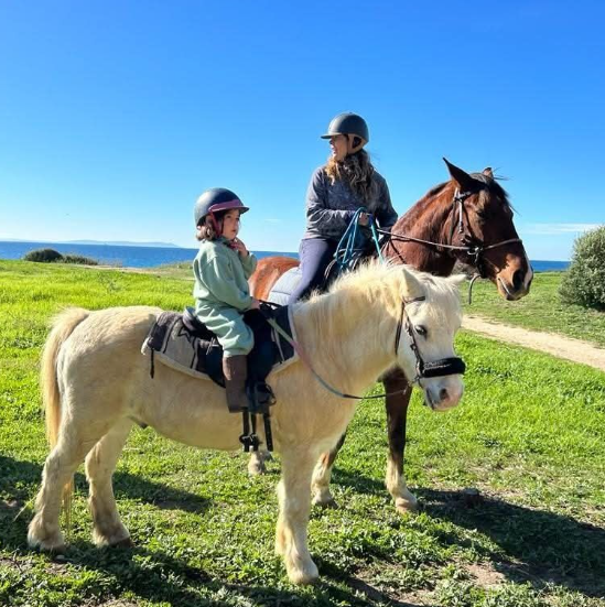 Niña con protecciones de seguridad a lomos de un pony